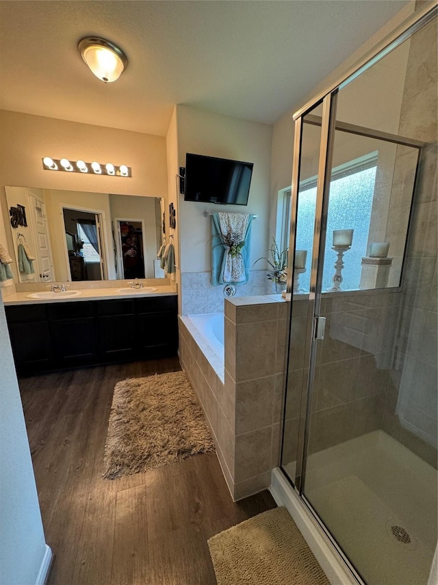 full bathroom with a stall shower, vanity, a garden tub, and wood finished floors