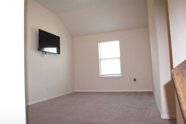 empty room featuring lofted ceiling, carpet, and baseboards