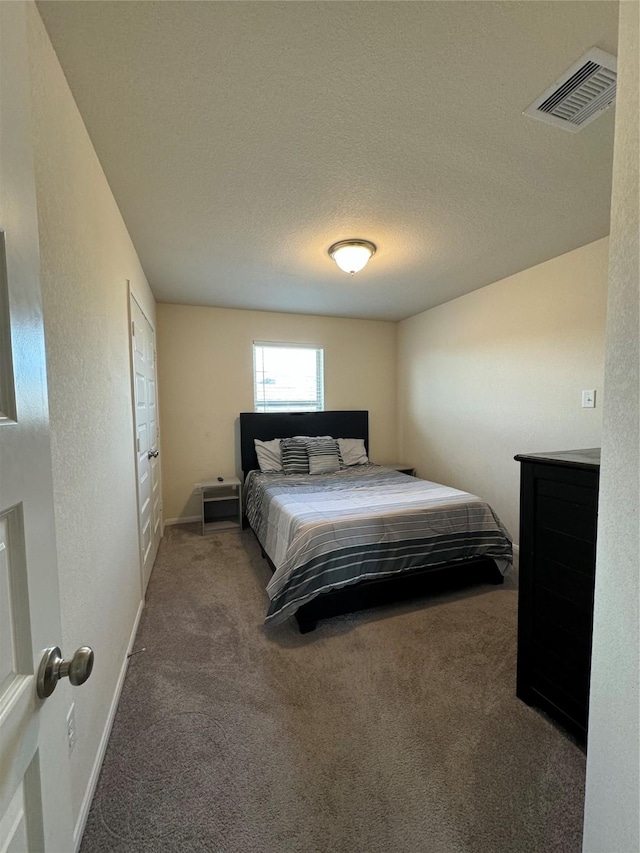 carpeted bedroom featuring visible vents, baseboards, and a textured ceiling