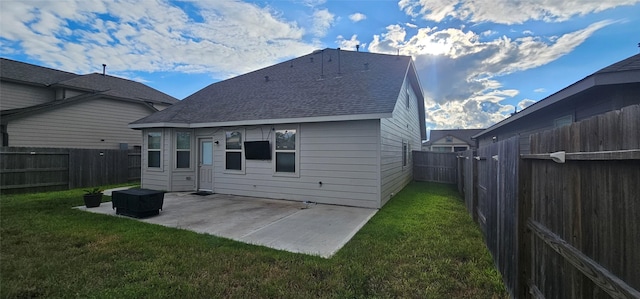 rear view of house with a lawn, roof with shingles, a fenced backyard, and a patio area