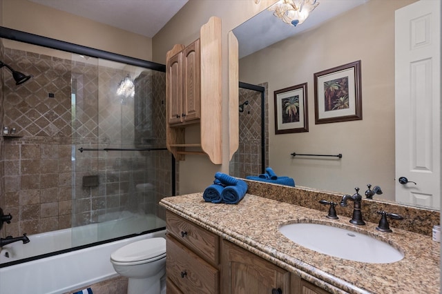 bathroom with toilet, vanity, and bath / shower combo with glass door