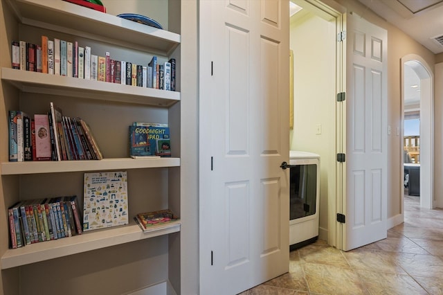 corridor with arched walkways, visible vents, washer / dryer, and baseboards