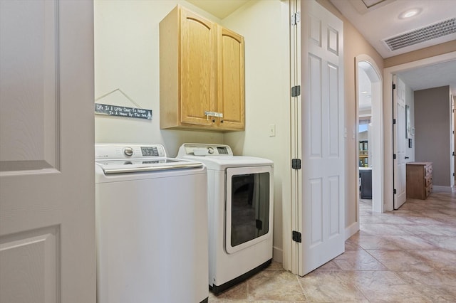 laundry area featuring visible vents, washing machine and dryer, cabinet space, arched walkways, and baseboards