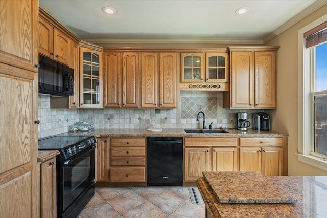 kitchen featuring black appliances, a sink, glass insert cabinets, decorative backsplash, and light stone countertops