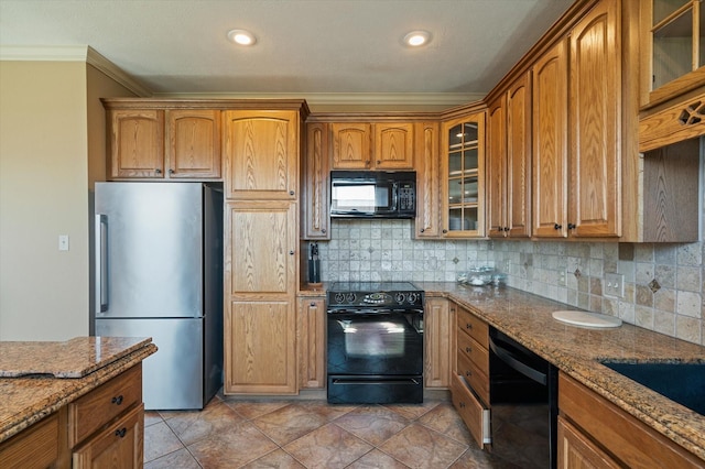 kitchen featuring brown cabinetry, stone countertops, black appliances, and tasteful backsplash