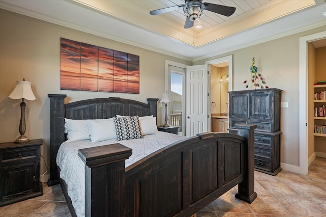 bedroom with ceiling fan, baseboards, a tray ceiling, ornamental molding, and ensuite bath