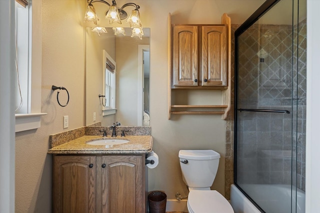 bathroom with vanity, toilet, and combined bath / shower with glass door