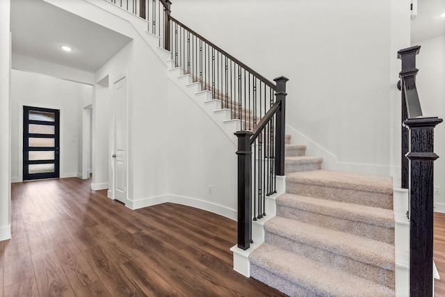 entrance foyer featuring stairs, a high ceiling, wood finished floors, and baseboards