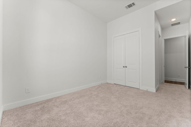 unfurnished bedroom with a closet, visible vents, carpet flooring, and baseboards