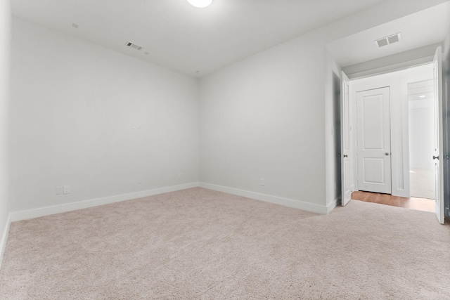 spare room featuring carpet flooring, baseboards, and visible vents