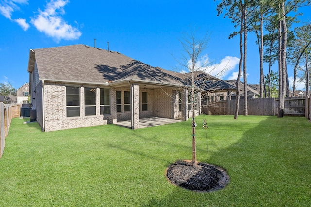 back of property featuring a yard, a fenced backyard, brick siding, and a shingled roof