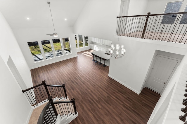 staircase featuring ceiling fan, baseboards, wood finished floors, and a towering ceiling