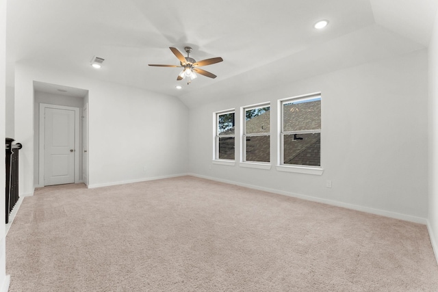 spare room with baseboards, visible vents, lofted ceiling, ceiling fan, and light colored carpet