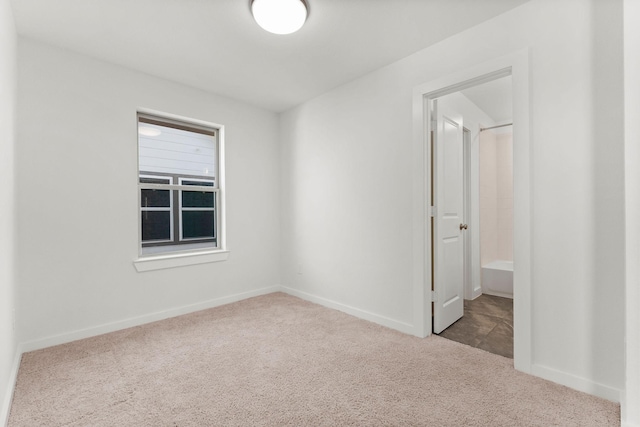 carpeted spare room featuring baseboards