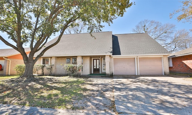 view of front of home with brick siding, concrete driveway, a garage, and roof with shingles