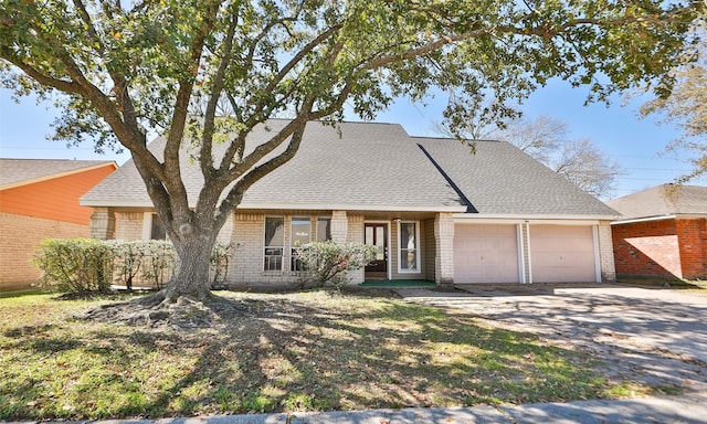 view of front facade with driveway, brick siding, an attached garage, and a shingled roof