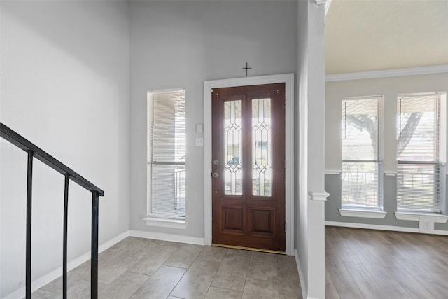 foyer entrance with a wealth of natural light, stairway, baseboards, and crown molding