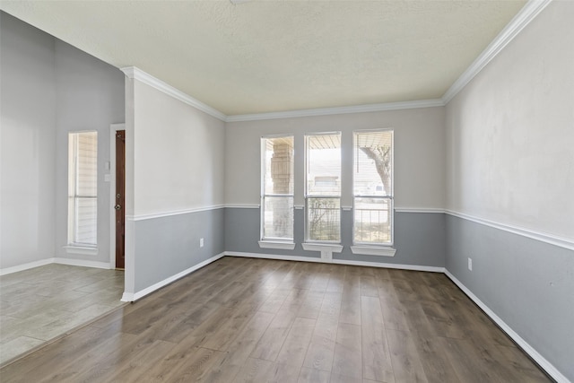 unfurnished room featuring baseboards, a textured ceiling, wood finished floors, and crown molding