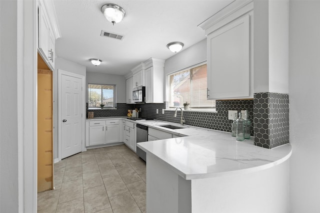 kitchen with visible vents, appliances with stainless steel finishes, a peninsula, white cabinets, and a sink