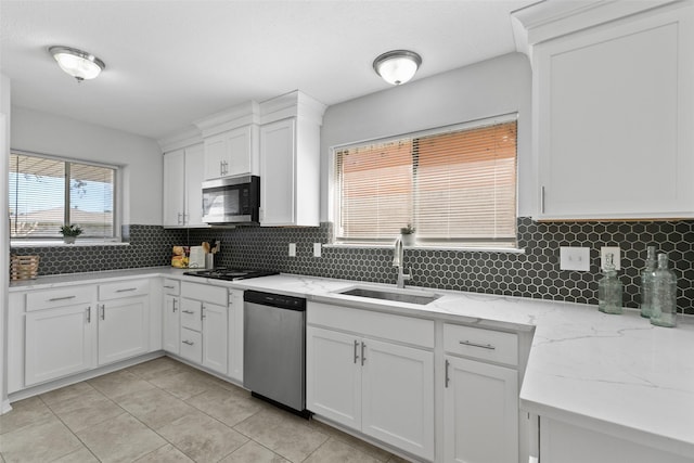 kitchen featuring a sink, stainless steel appliances, decorative backsplash, and white cabinetry