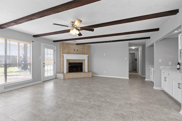 unfurnished living room featuring beam ceiling, a fireplace, baseboards, and ceiling fan