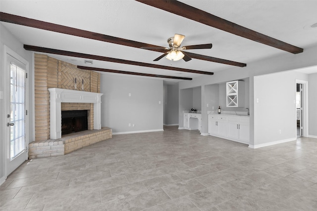 unfurnished living room featuring a bar, beam ceiling, a brick fireplace, and baseboards