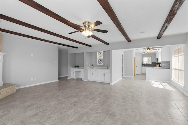 unfurnished living room with ceiling fan, a fireplace, baseboards, and a sink