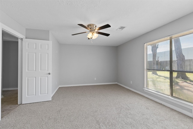 carpeted empty room featuring visible vents, baseboards, a textured ceiling, and ceiling fan