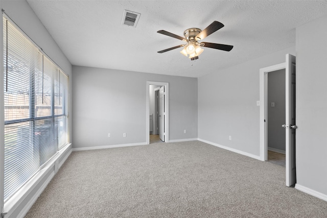 unfurnished bedroom with light carpet, visible vents, a textured ceiling, and baseboards