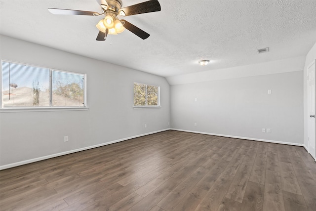 empty room with visible vents, a textured ceiling, lofted ceiling, and wood finished floors