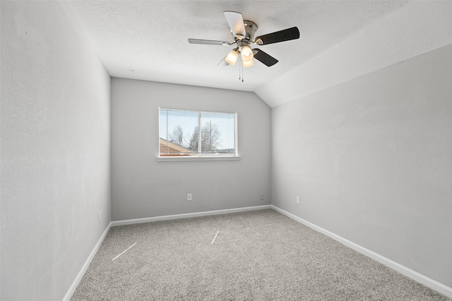 carpeted empty room featuring baseboards, a textured ceiling, lofted ceiling, and ceiling fan