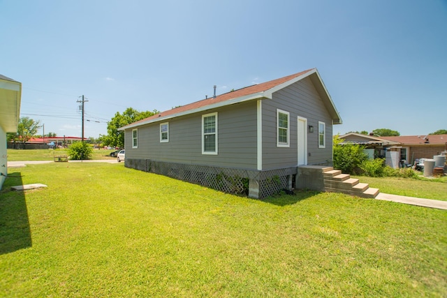 view of side of property featuring entry steps and a lawn