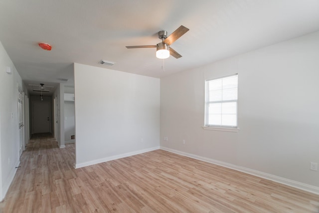 unfurnished room with light wood-type flooring, visible vents, baseboards, attic access, and ceiling fan