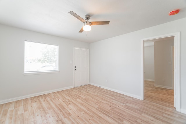 empty room with baseboards, light wood finished floors, and ceiling fan