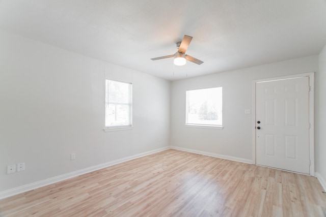 unfurnished room with a wealth of natural light, baseboards, light wood-style flooring, and ceiling fan