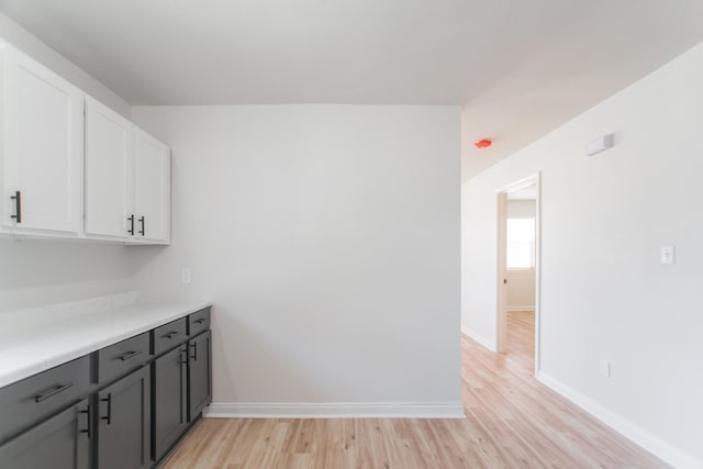 kitchen with baseboards, white cabinets, light countertops, and light wood finished floors