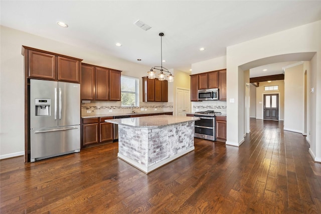 kitchen featuring tasteful backsplash, visible vents, dark wood finished floors, light stone counters, and stainless steel appliances