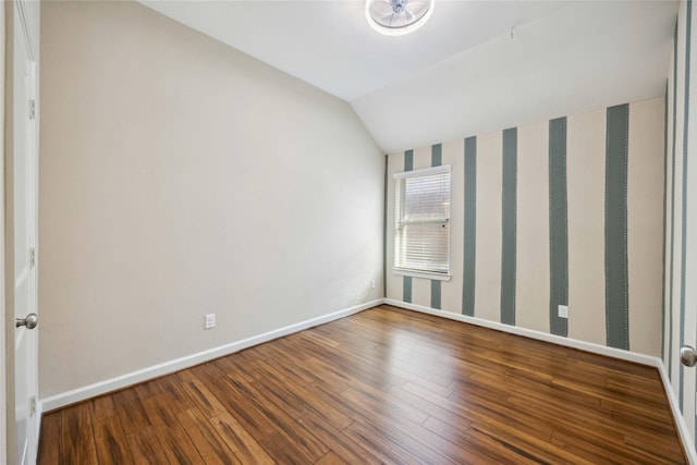 unfurnished room featuring vaulted ceiling, wood finished floors, and baseboards