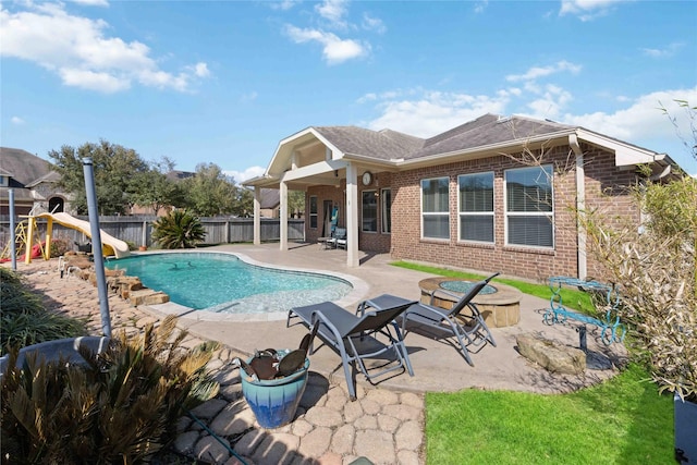 view of pool featuring a fenced backyard, an outdoor fire pit, a water slide, a fenced in pool, and a patio area