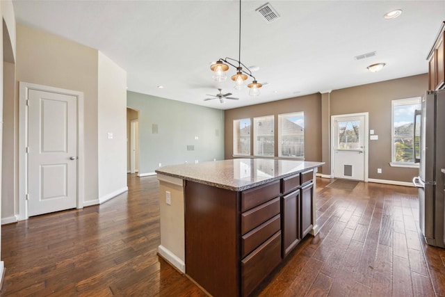 kitchen with dark wood-type flooring, plenty of natural light, freestanding refrigerator, and a kitchen island