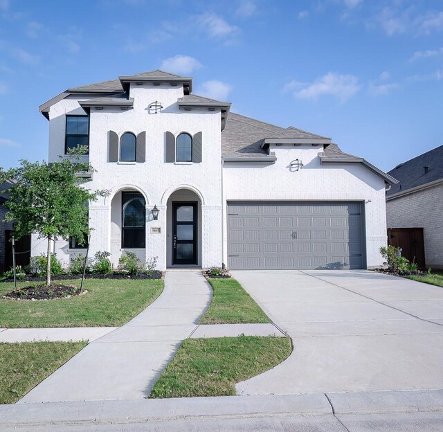 view of front of property with an attached garage, roof with shingles, concrete driveway, and a front yard