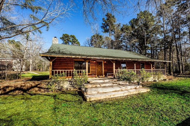 view of front of home with a front yard, covered porch, and a chimney