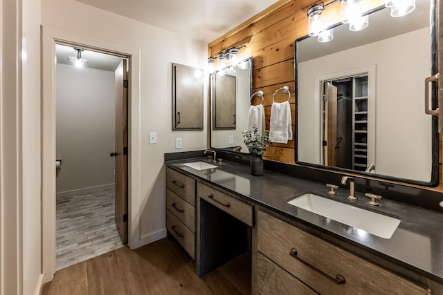 bathroom with a sink, baseboards, wood finished floors, and double vanity