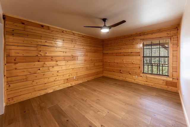 unfurnished room with ceiling fan, a sauna, wooden walls, and wood finished floors