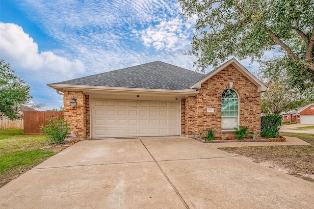 view of front of home featuring a shingled roof, brick siding, concrete driveway, and fence