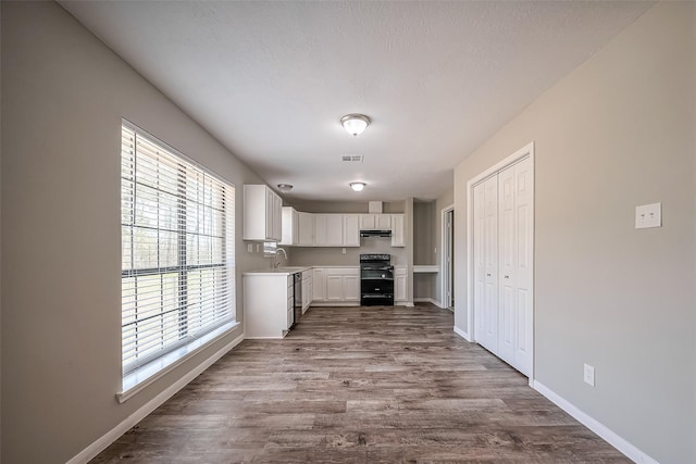 kitchen featuring light countertops, range, dark wood-style floors, white cabinetry, and a sink