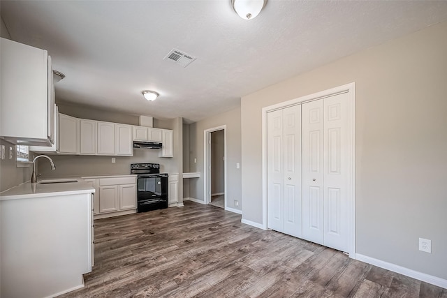 kitchen with visible vents, a sink, under cabinet range hood, white cabinetry, and black / electric stove