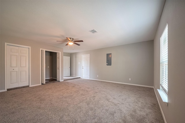 unfurnished bedroom featuring visible vents, multiple closets, electric panel, carpet floors, and baseboards