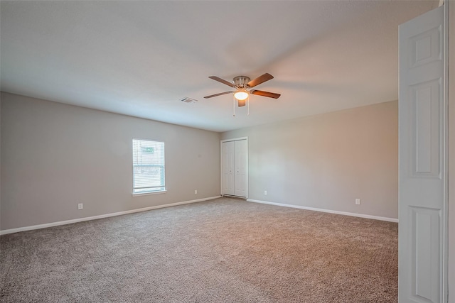 empty room featuring visible vents, carpet flooring, a ceiling fan, and baseboards