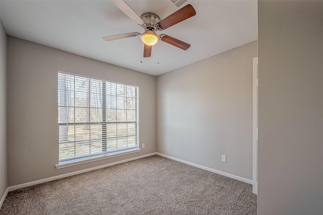 carpeted spare room featuring baseboards and a ceiling fan